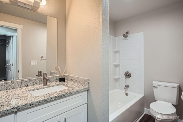 bathroom with shower / bathtub combination, a textured wall, toilet, vanity, and baseboards