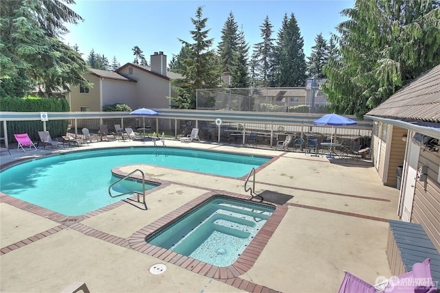 community pool with a patio area, fence, and a community hot tub