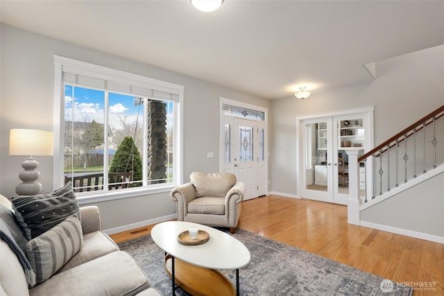 living area featuring french doors, visible vents, wood finished floors, baseboards, and stairs