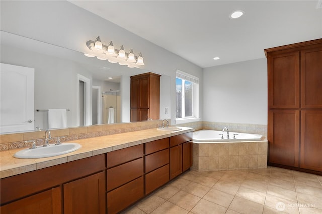 bathroom featuring a bath, tile patterned flooring, double vanity, and a sink