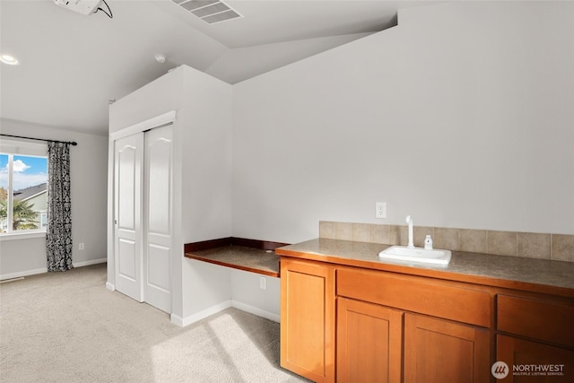 interior space with vaulted ceiling, vanity, visible vents, and baseboards