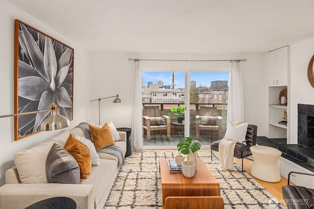 living room with built in features, a fireplace with raised hearth, and wood finished floors