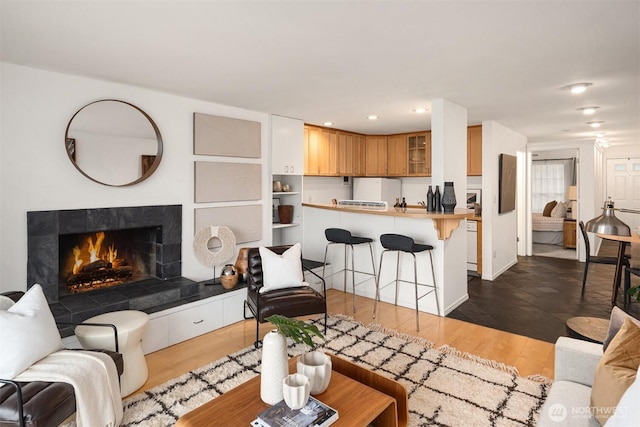 living area featuring recessed lighting, dark wood-type flooring, and a tile fireplace