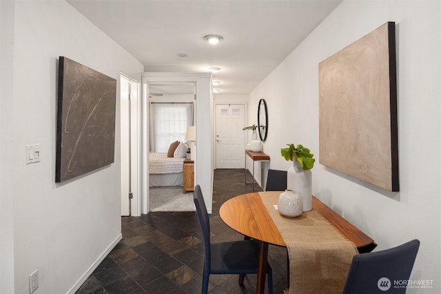 corridor with stone finish floor and baseboards