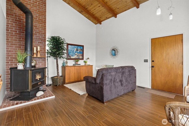 living area with a wood stove, wood ceiling, dark wood finished floors, and beam ceiling