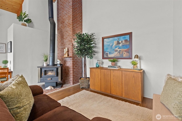 living room with high vaulted ceiling, light wood-type flooring, a wood stove, and wooden ceiling