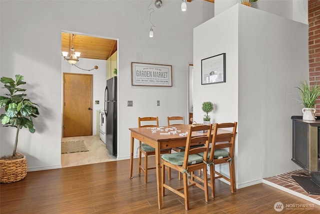 dining space with baseboards, an inviting chandelier, and wood finished floors