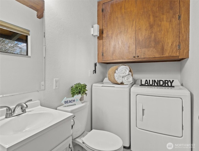 half bathroom with toilet, a textured wall, washer and dryer, and vanity