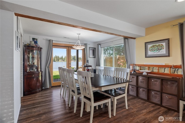 dining room with dark wood-style floors, french doors, and a water view