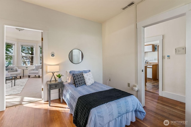 bedroom with wood-type flooring, visible vents, and baseboards