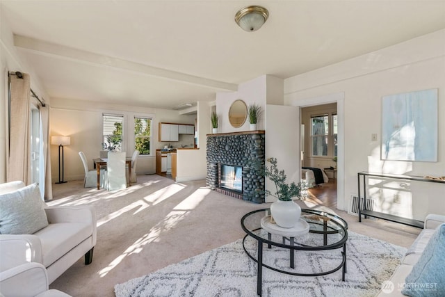 living room featuring carpet floors, a tile fireplace, and beamed ceiling