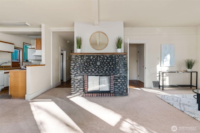 living area featuring a tiled fireplace, visible vents, beam ceiling, and light colored carpet