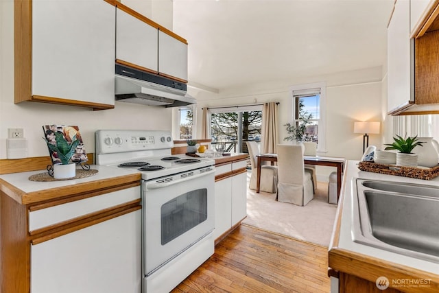 kitchen featuring under cabinet range hood, white electric range, white cabinetry, light countertops, and light wood finished floors