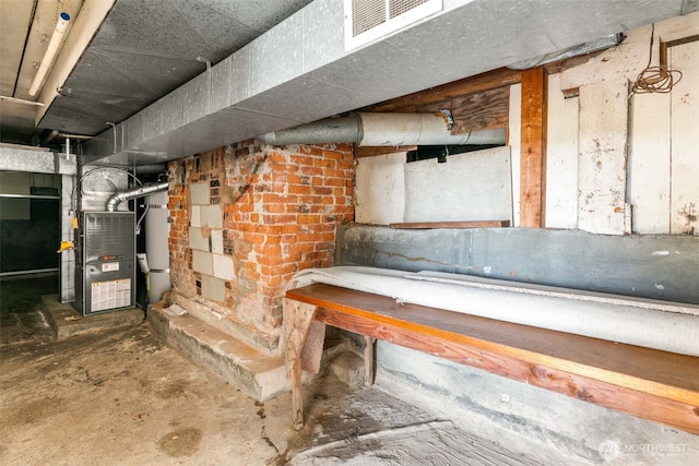 unfinished below grade area with strapped water heater, visible vents, and heating unit