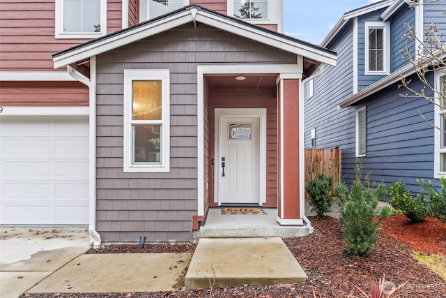 view of exterior entry featuring a garage and fence