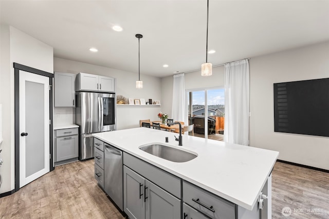 kitchen with stainless steel appliances, light wood-style floors, a sink, and gray cabinetry