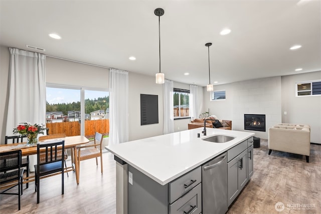 kitchen with gray cabinets, light countertops, visible vents, stainless steel dishwasher, and a sink