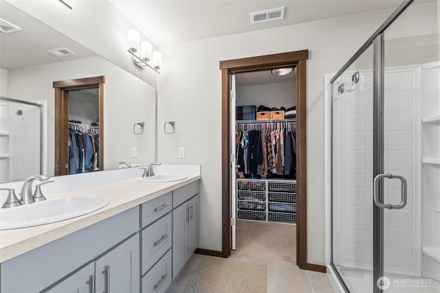 bathroom featuring a stall shower, a sink, and visible vents