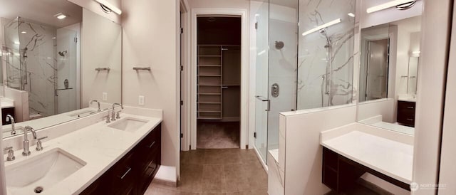 full bath with a spacious closet, double vanity, a sink, and a marble finish shower