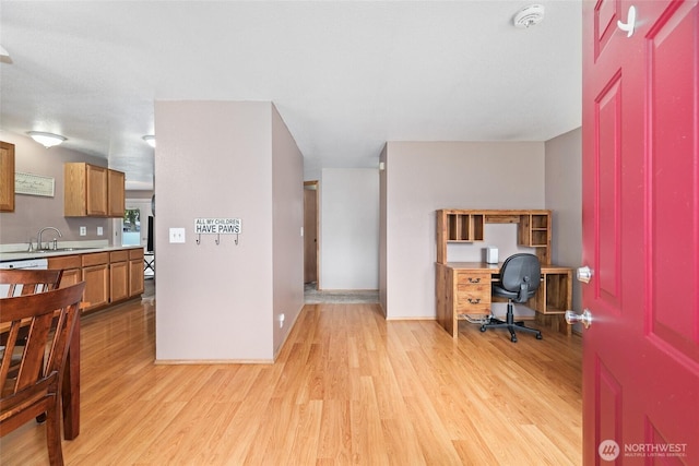 office space with baseboards, light wood-style floors, and a sink