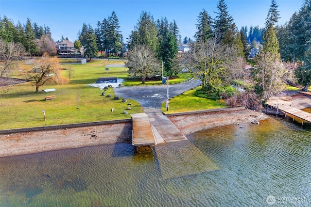 surrounding community featuring a lawn, driveway, a boat dock, and a water view