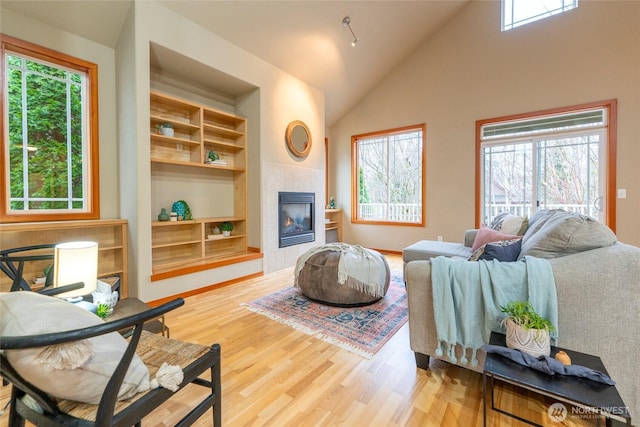 living room with vaulted ceiling, a fireplace, wood finished floors, and built in features