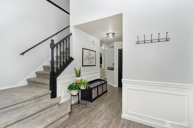 stairway featuring a wainscoted wall, a decorative wall, and wood finished floors