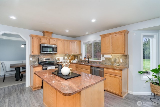 kitchen with stainless steel appliances, light brown cabinets, a sink, and a kitchen island