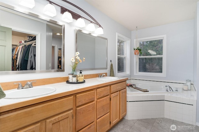 bathroom featuring double vanity, tile patterned flooring, a sink, and a bath