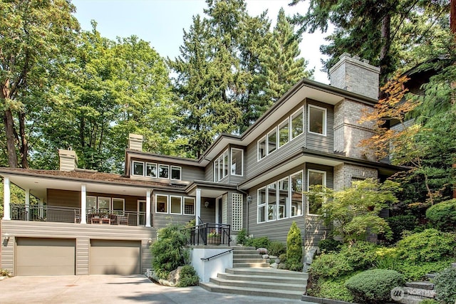 view of front of house featuring driveway, stairway, a chimney, and an attached garage