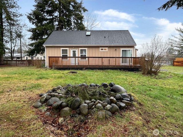 back of property featuring a yard, roof with shingles, fence, and a deck