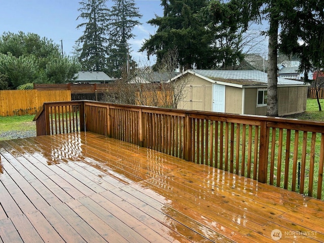 wooden deck with a shed, fence, and an outdoor structure