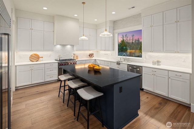 kitchen featuring appliances with stainless steel finishes, a center island, white cabinets, and a kitchen breakfast bar