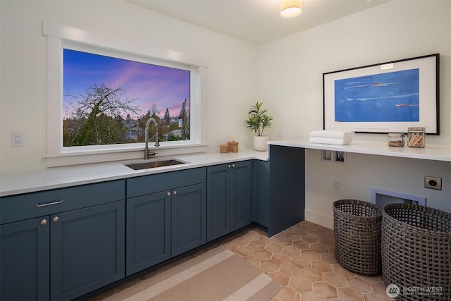 interior space featuring light tile patterned floors, light countertops, a sink, and blue cabinets