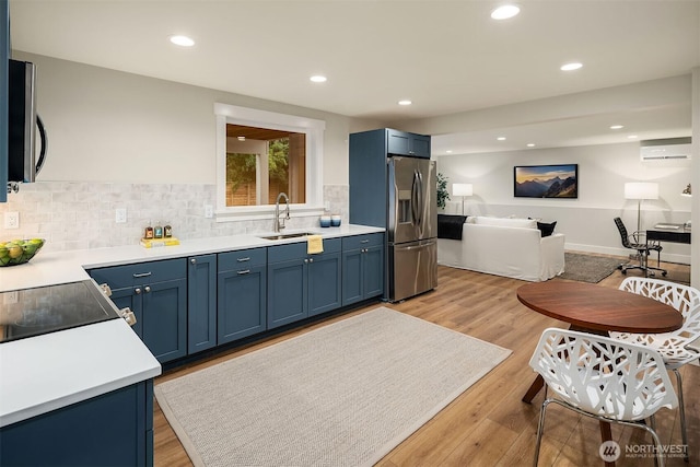 kitchen featuring stainless steel appliances, blue cabinets, light countertops, and a sink