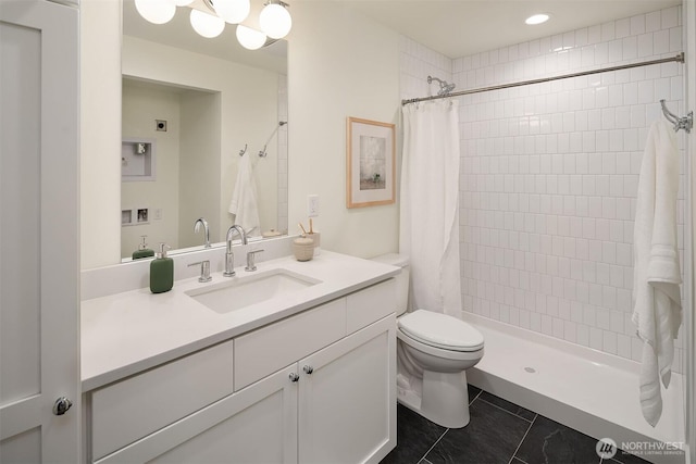 full bathroom with tiled shower, vanity, and toilet