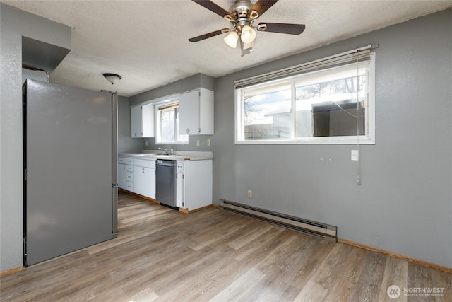 kitchen with light wood finished floors, stainless steel appliances, baseboard heating, light countertops, and white cabinetry