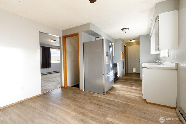 kitchen with a baseboard heating unit, white cabinets, light countertops, and stainless steel fridge with ice dispenser