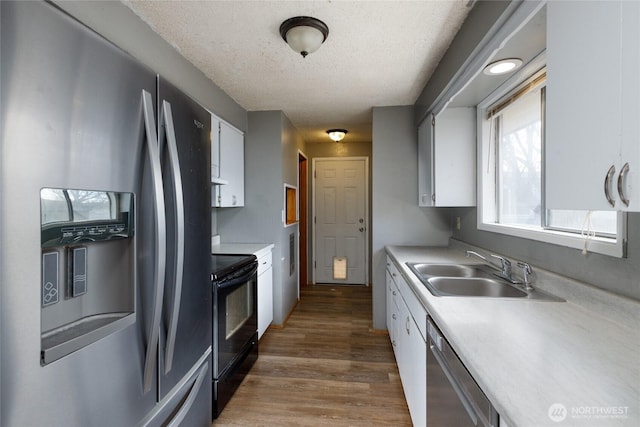 kitchen with dark wood-style floors, light countertops, appliances with stainless steel finishes, white cabinets, and a sink