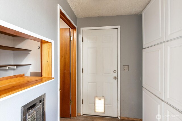 hallway featuring heating unit and a textured ceiling