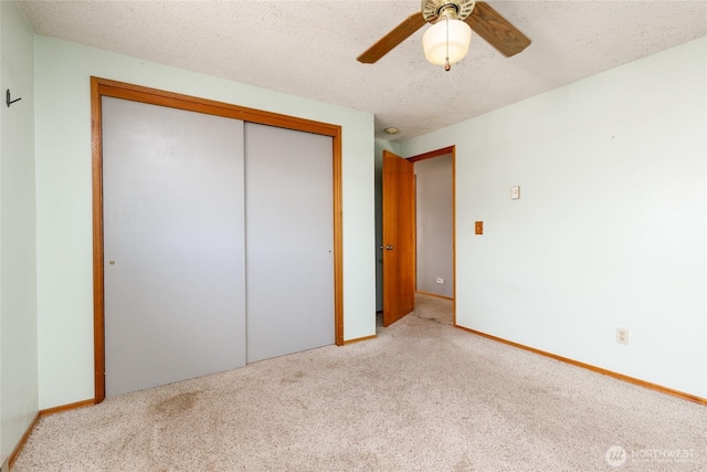 unfurnished bedroom featuring ceiling fan, a closet, a textured ceiling, and light colored carpet