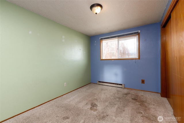 spare room featuring a textured ceiling, carpet floors, and baseboard heating