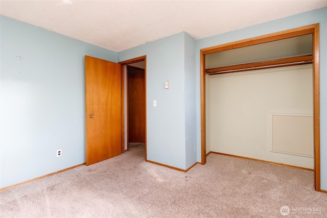 unfurnished bedroom with a closet, light carpet, and baseboards