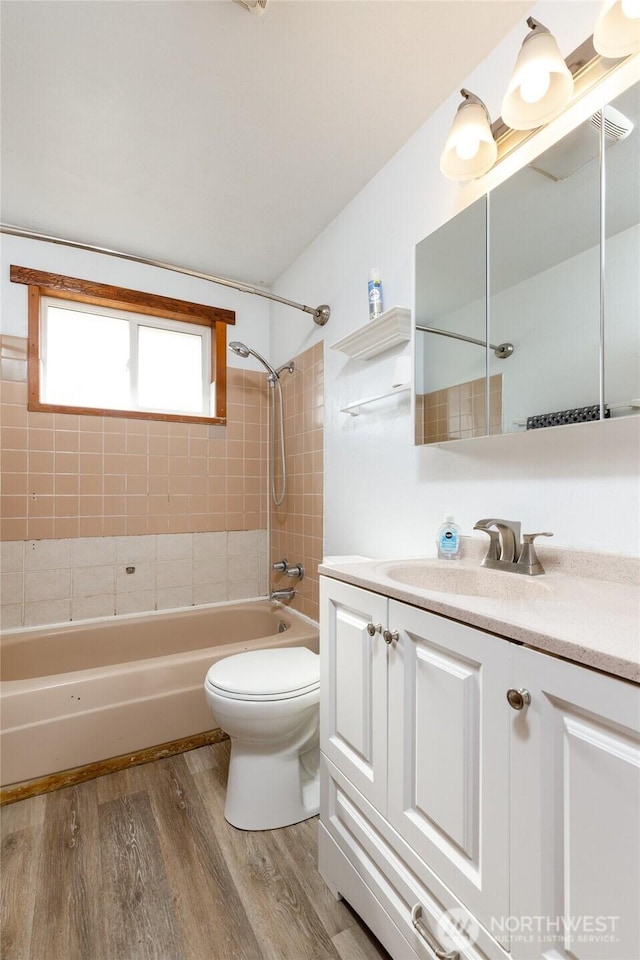 bathroom with toilet, bathtub / shower combination, wood finished floors, and vanity