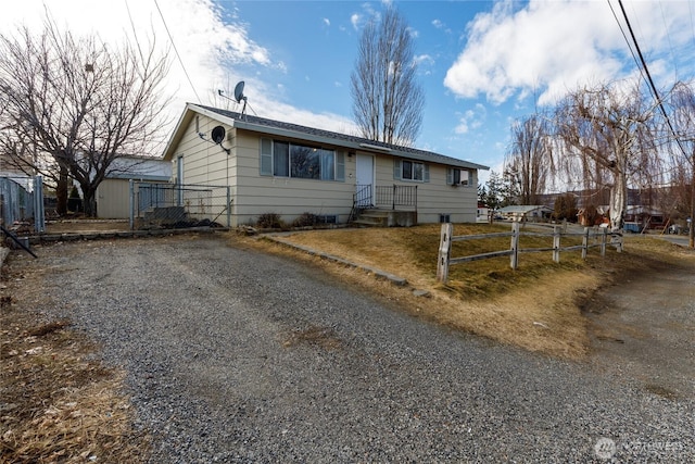 ranch-style house with gravel driveway and fence