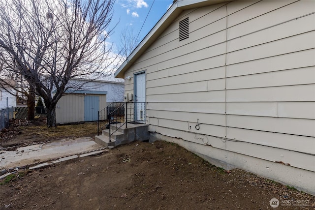 view of home's exterior with fence, a storage unit, and an outbuilding