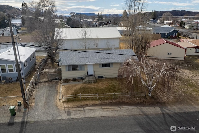 view of front of house with a mountain view, a shingled roof, fence, and a residential view