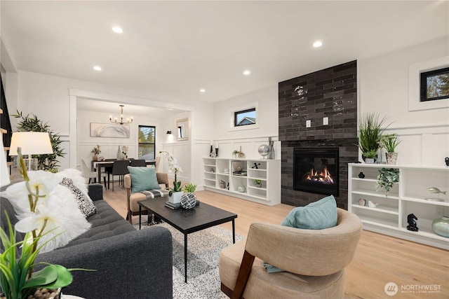 living area with light wood-style floors, a fireplace, a decorative wall, and recessed lighting