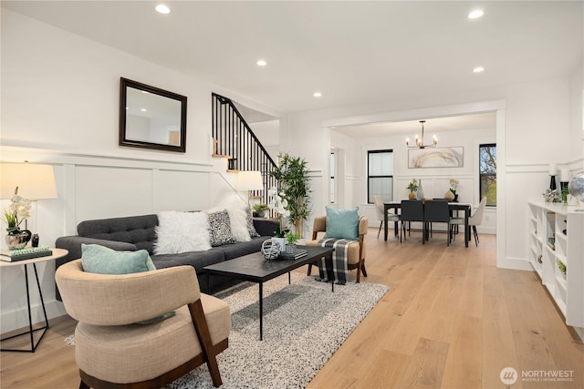 living area with light wood finished floors, an inviting chandelier, stairs, a decorative wall, and recessed lighting