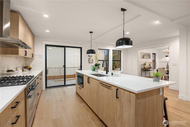 kitchen featuring light countertops, wall chimney range hood, high end range, and decorative light fixtures